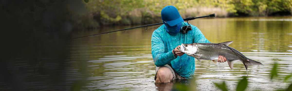 Angler kneeling in the shallows holding a tarpon